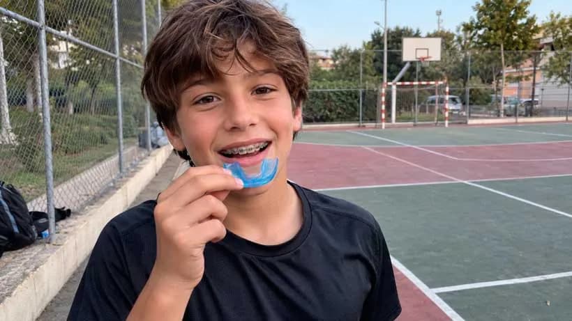 Niño con brackets y protector bucal preparado para un entrenamiento deportivo