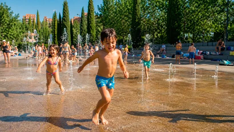 Niños jugando en los chorros de agua de la playa urbana de Madrid Río en una tarde de verano